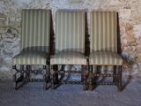 three chairs sitting next to each other in front of a stone wall
