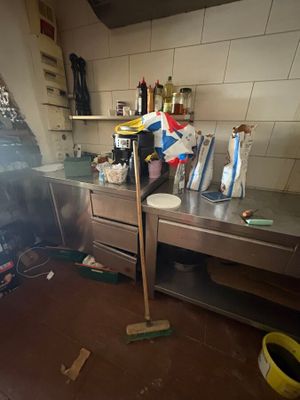 a dirty kitchen with a lot of clutter on the floor