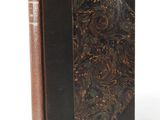 an old book with a brown cover sitting on top of a white surface