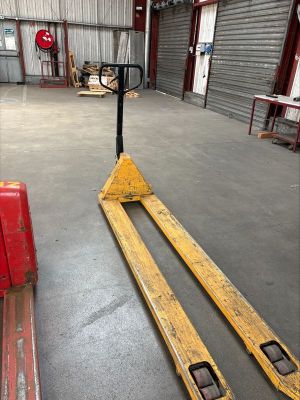 a forklift in a warehouse with a red object in the foreground