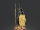 statue d'un homme tenant un bâton et une horloge, posée sur un socle