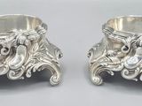 two silver vases sitting on a table next to each other
