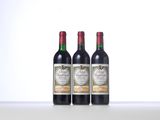 three bottles of red wine sitting on top of a table