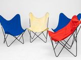 trois chaises pliantes recouvertes de housses rouges, bleues et jaunes