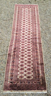 un tapis rouge et blanc posé sur un sol recouvert de gravier