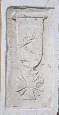 une plaque apposée sur le mur d'un immeuble, sur laquelle figure un vase