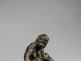 une statue en bronze représentant un homme assis par terre