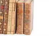 several old books are stacked on top of each other on a white surface