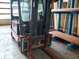 a forklift in a warehouse with shelves and pallets