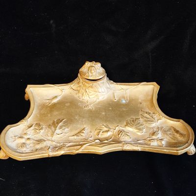 a gold plate with a frog on it on a black background