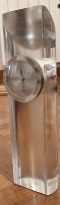 a silver clock sitting on top of a glass block