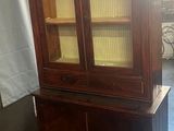 une vieille armoire en bois avec des portes vitrées dans une pièce