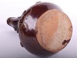 a brown vase with a brown lid sitting on a white surface