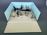 une maquette d'avion dans une boîte, avec des personnes debout tout autour