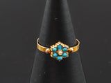 une bague en or sertie de turquoises sur un cône noir
