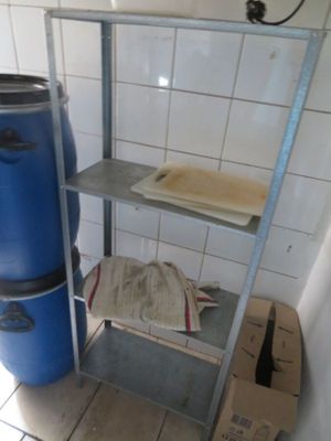 un seau bleu posé à côté d'une étagère métallique dans une salle de bains