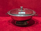 un grand pot en argent muni d'un couvercle, posé sur un support rouge