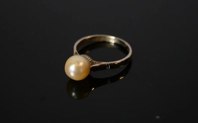 un gros plan d'une bague ornée d'une perle sur un fond noir