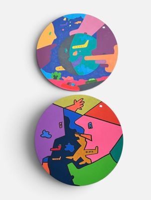 two round coasters with colorful designs on them on a white surface