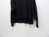 a black sweater hanging on a wall with a white background