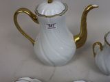 a white and gold tea set with four cups and saucers