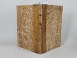 un vieux livre à la couverture en bois posé sur une surface blanche