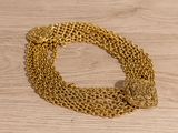 a close up of a gold chain bracelet on a wooden surface