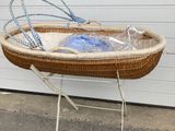 a wicker baby bassine on a stand in front of a garage