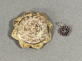 une broche en or et une paire de boucles d'oreilles posées sur une table