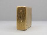 une photo d'un briquet doré posé sur une table blanche
