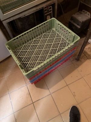 une personne debout dans une cuisine, avec un panier posé par terre
