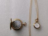 a close up of a gold pocket watch with a chain on a white surface