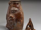 un vase marron et une petite figurine posés l'un à côté de l'autre