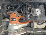 une ponceuse électrique orange et noire posée sur une boîte noire