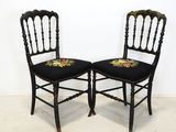 paire de chaises anciennes noires avec des coussins d'assise brodés de motifs floraux