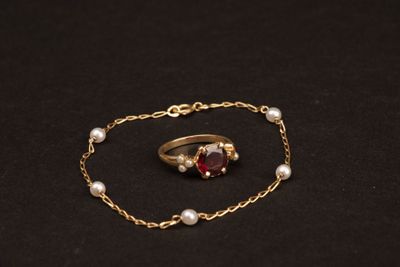 un gros plan sur un bracelet à chaîne en or orné d'une pierre rouge et de perles