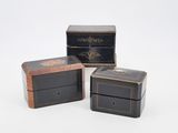 three black and gold boxes sitting next to each other on a white surface