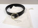 black leather belt with a gold buckle on a white table