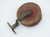 a wooden spool with a metal handle on a white surface