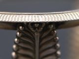 a close up of a silver plate with a leaf design on it