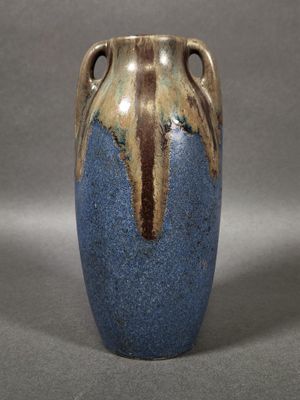 un vase bleu et marron posé sur une surface grise