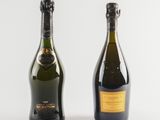 two bottles of champagne sitting next to each other on a white surface