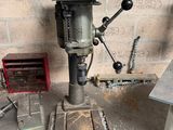 une perceuse posée sur une table dans une pièce où se trouvent de nombreux outils