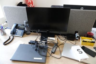 a desk with two monitors, a laptop, a phone, and other electronics on it