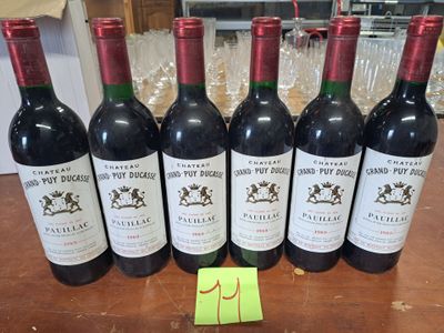 six bouteilles de vin rouge sont alignées sur une table
