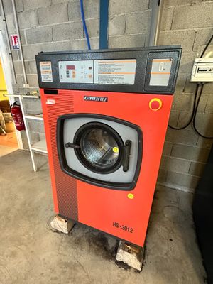 a red washing machine in a garage next to a ladder