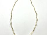 a close up of a white pearl necklace on a white surface