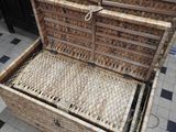 a wicker chest with a lid open on a tiled floor