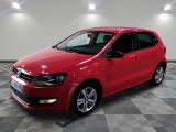 a red volkswagen polo is parked in a large room