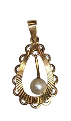 un gros plan d'un pendentif en or serti d'une perle